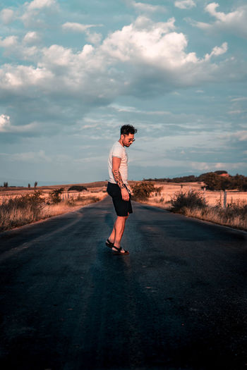 Side view of man standing on road against sky