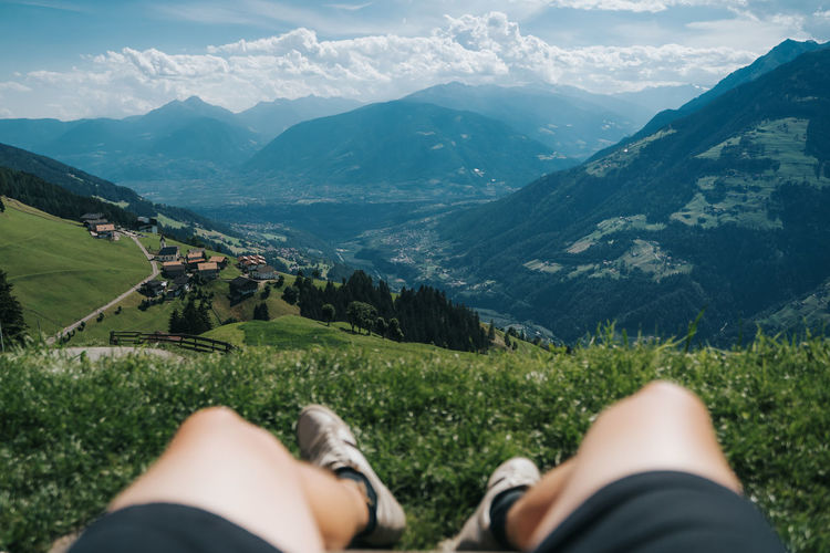 Low section of man relaxing on land against mountains