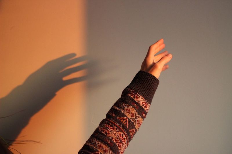 Close-up of hand on wall at sunset