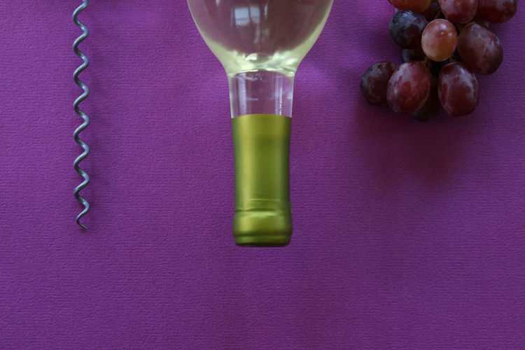 High angle view of wine bottle by grapes on table
