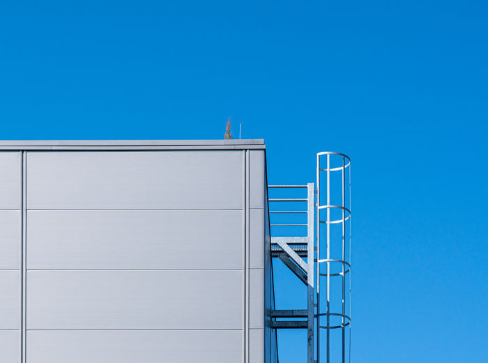 Low angle view of building with fire escape against clear blue sky