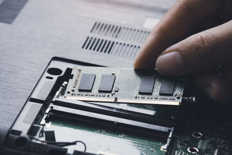Technician install new ram random-access memory to memory slot on laptop motherboard