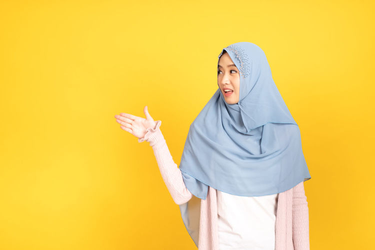 Woman standing against yellow background