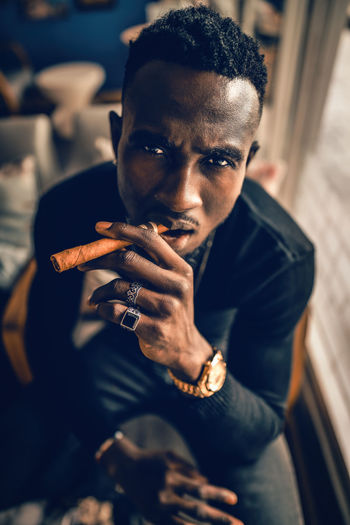 Portrait of african american man holding cigar on hand in coffee shop.