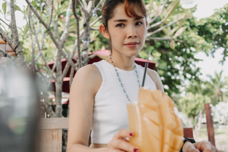 Happy woman drinks mango juice smoothie in summer day.