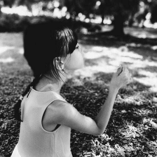 Side view of girl making wish while holding dandelion flower