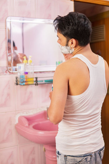 Rear view of man standing in bathroom at home