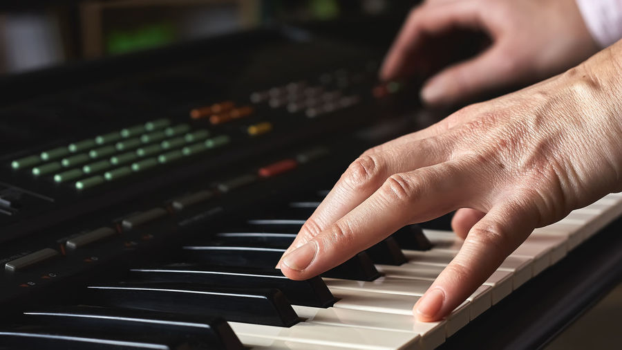 Female musician playing the digital piano or electronic keyboard at home. music education online