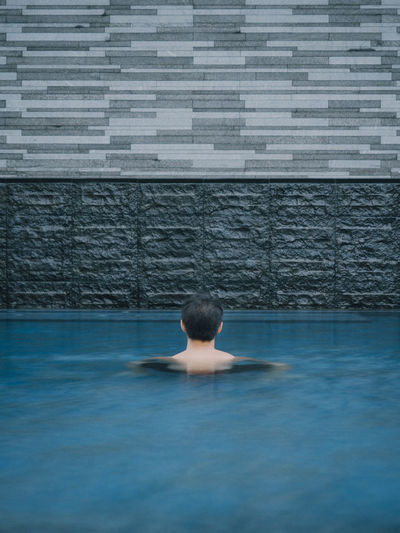 Back of asian male head in pool looking at layers