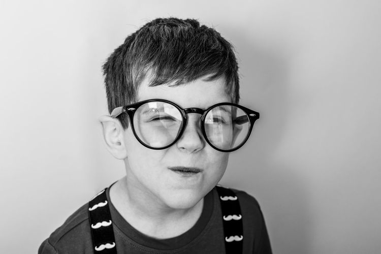 Portrait of boy wearing eyeglasses against white background