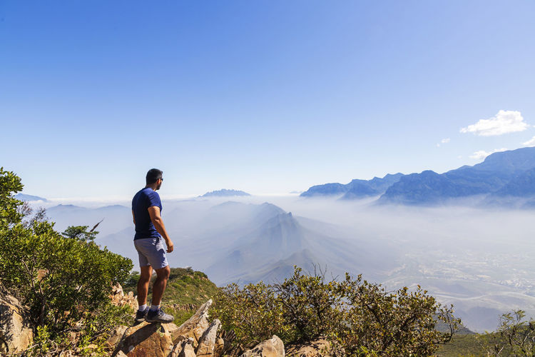 Man looking at mountains against blue sky