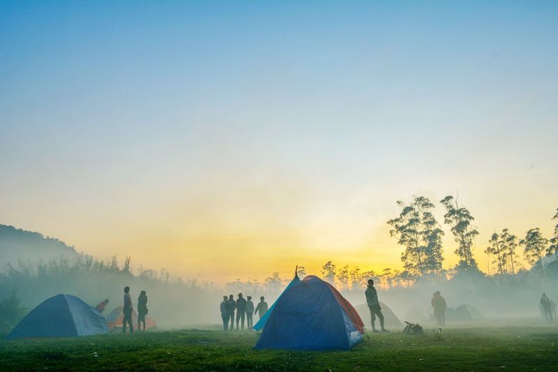 People camping against sky during sunrise