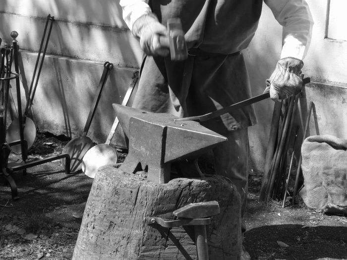 Midsection of man working on anvil at workshop