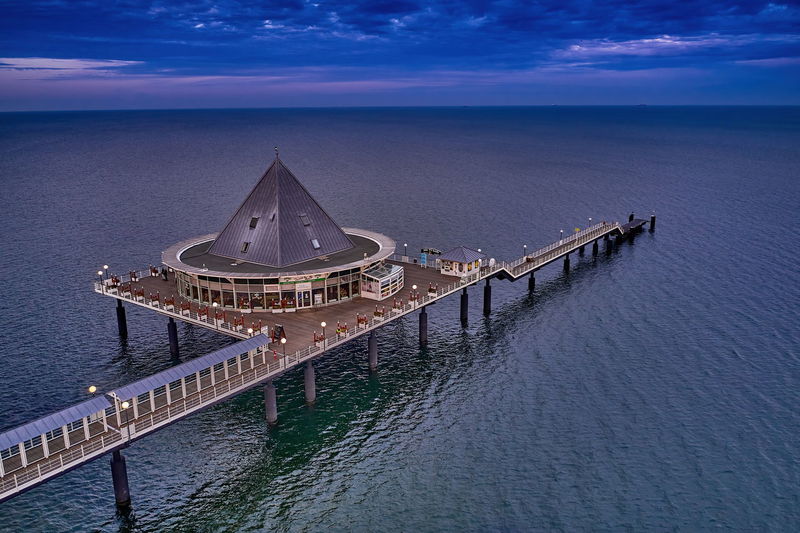 High angle view of illuminated building by sea against sky