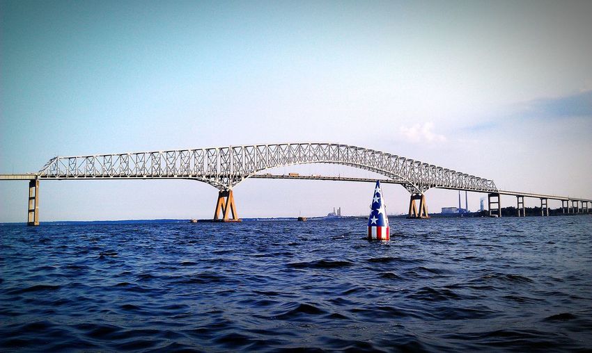 American flag on distance marker in sea against francis scott key bridge