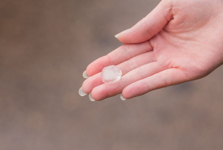 Close-up of woman holding hands against blurred background