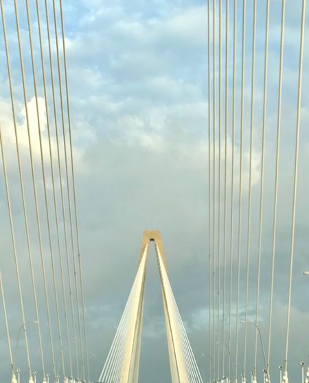 Suspension bridge against cloudy sky
