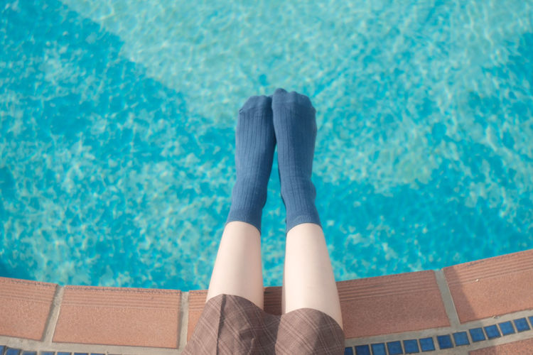 Low section of woman relaxing by swimming pool