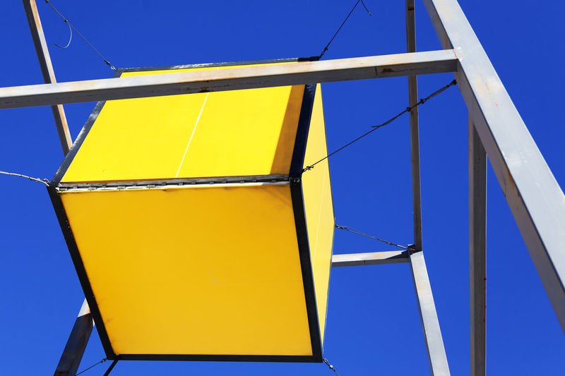 Large yellow cube hanging outside a hardware store
