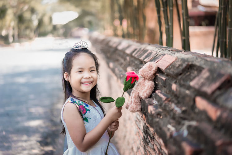 Portrait of cute girl smiling while standing on plant