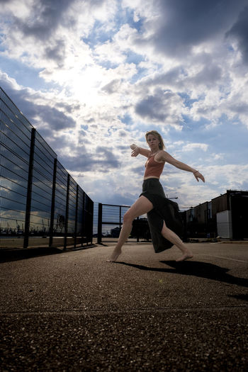 Woman with arms outstretched against sky in city