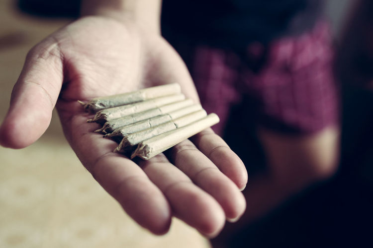 Cropped hand of man holding marijuana joint