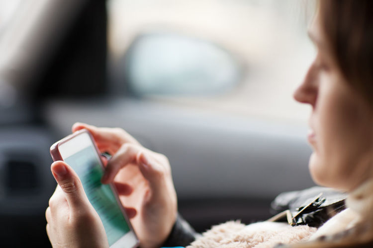 Side view of woman using mobile phone in car