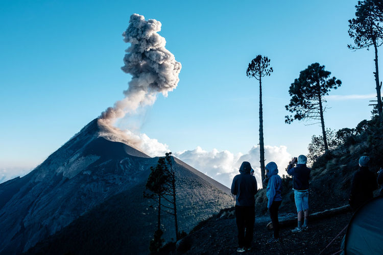 Rear view of hikers looking at acatenango volcano against blue sky
