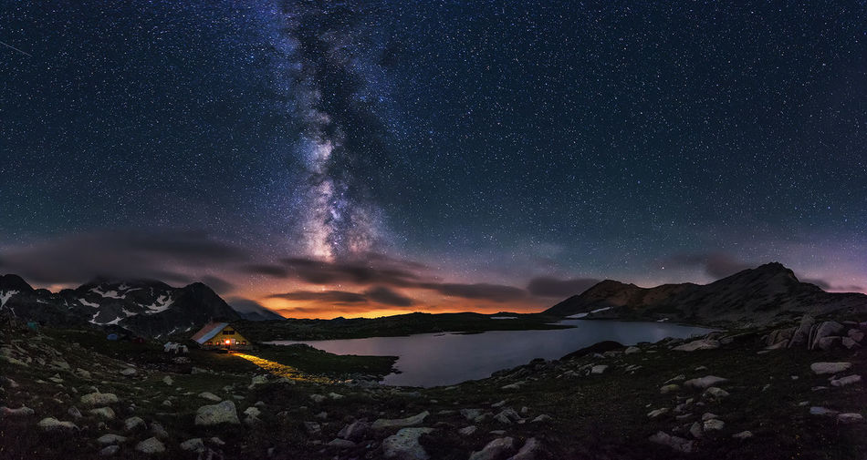 Scenic view of lake by mountains against star field