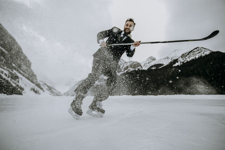 Smiling hockey player wearing suit stops fast on frozen lake louise