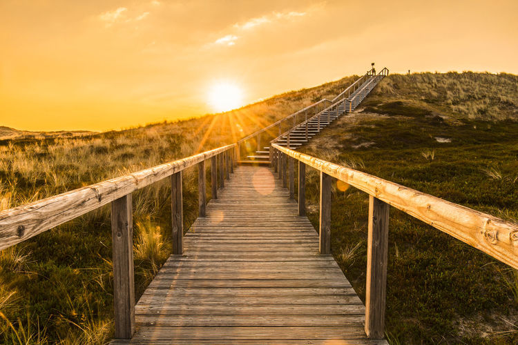 Sylt island sunrise scenery with wooden stairs over the sand dune. natural parkland at north sea.