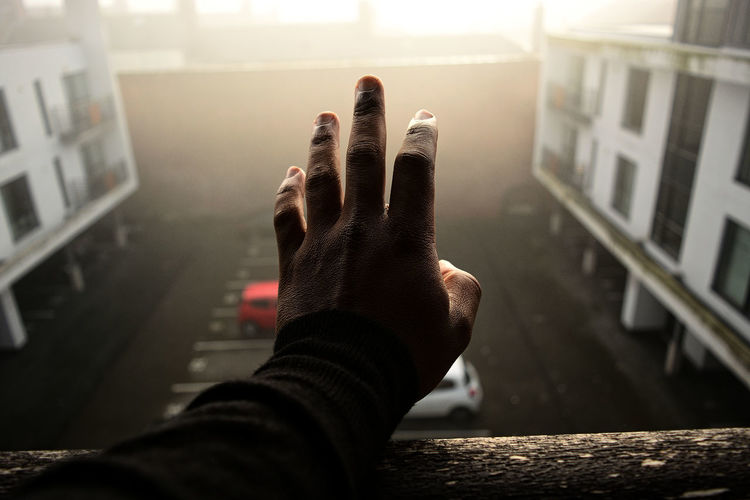Cropped hand on man on railing at morning during foggy weather