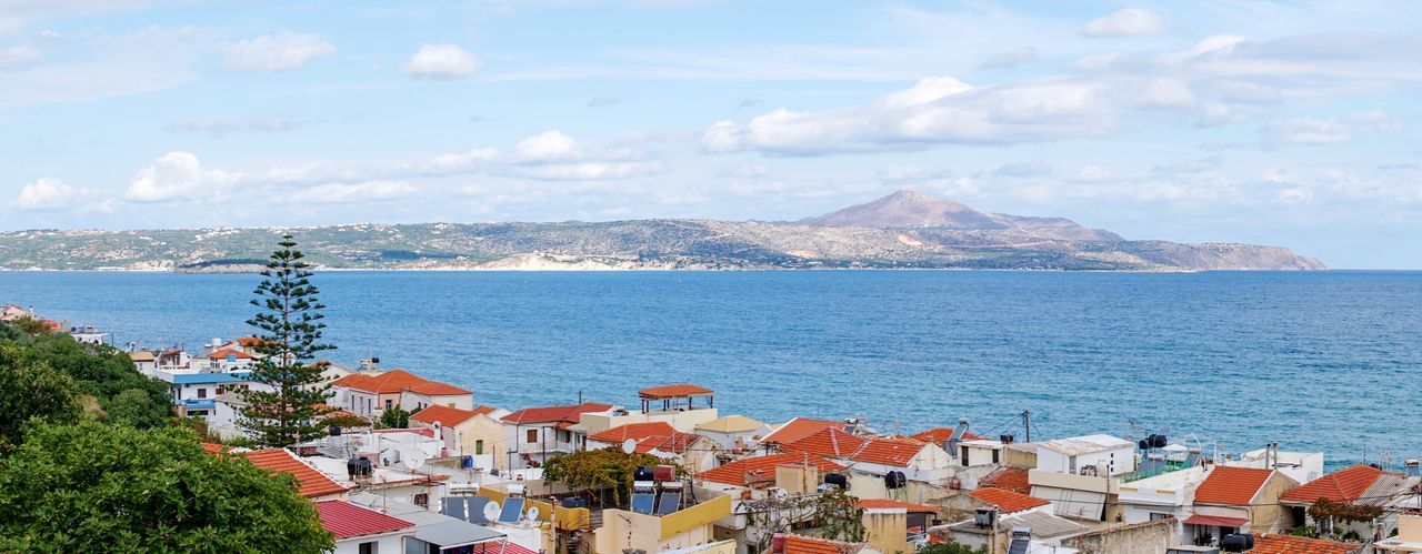 View of houses in sea against cloudy sky