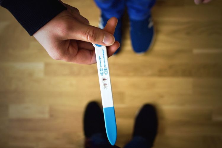Low section of woman holding pregnancy test