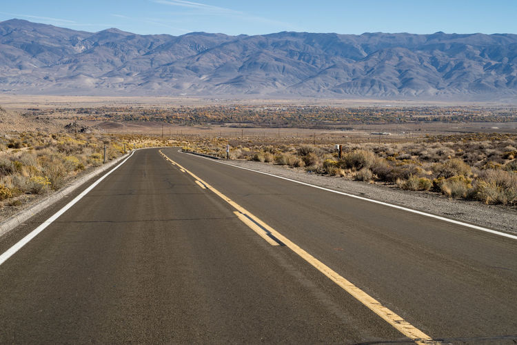 Empty road along desert landscape toward distant mountains