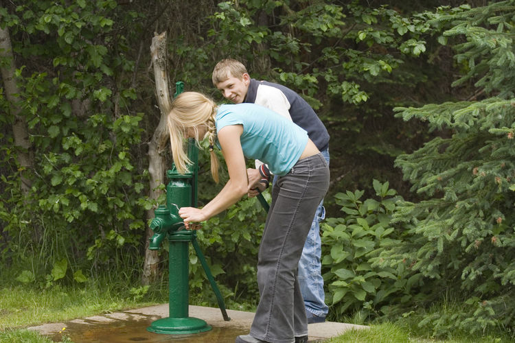 Siblings using hand pump against plants
