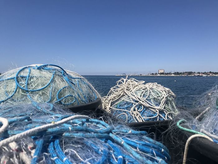 Fishing net on beach against clear blue sky