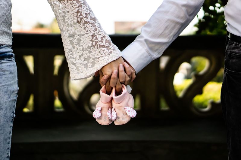 Cropped image of couple holding hands and baby booties
