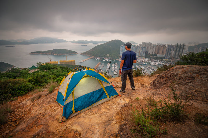 Man traveler taking photo on top of mountains near of tent camping