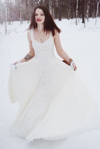 Portrait of beautiful young woman wearing white dress while standing on snow