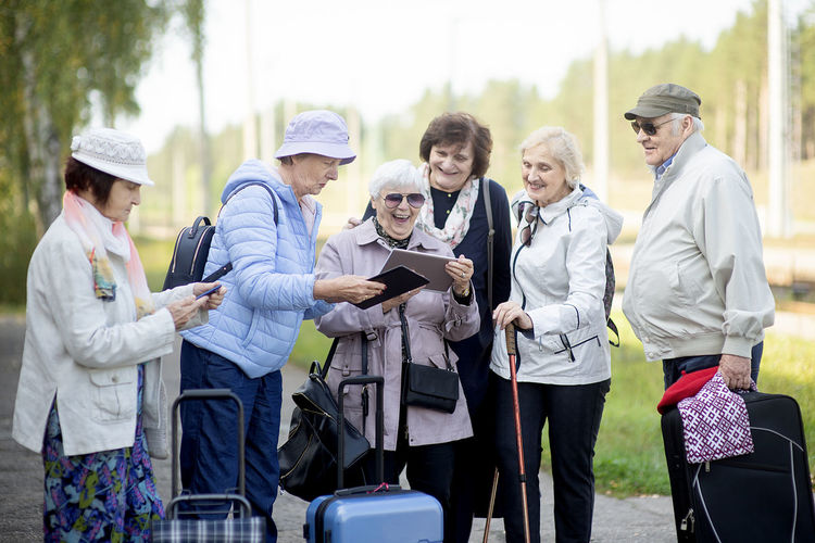 Group of senior elderly people looking at digital map on traveling journey during pandemic covid-19 