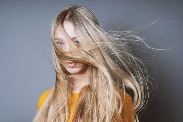 Close-up portrait of woman against gray background