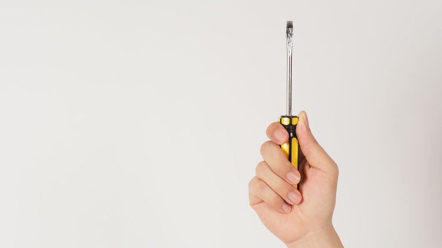 Cropped hand holding thermometer against white background