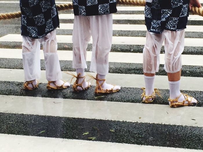 Low section of people standing on zebra crossing during rainy season