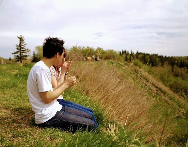Side view of young man sitting on land