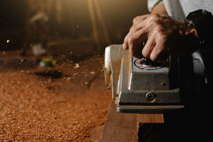 Close-up of a carpenter using a circular saw or a tool to cut wooden planks to make furniture  