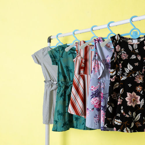 Clothes hanging on rack against wall against yellow background