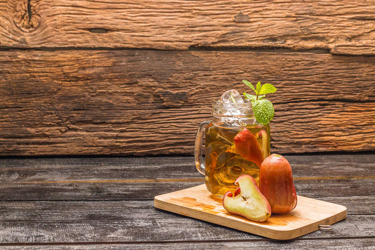 Drink by malay apple in mason jar on cutting board over wooden table