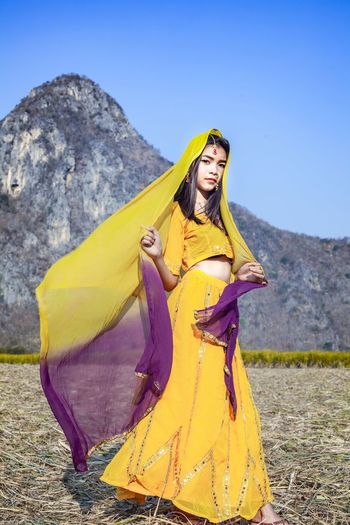Woman standing on yellow umbrella against mountain