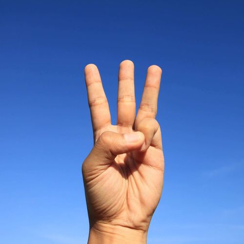 Close-up of human hand against clear blue sky